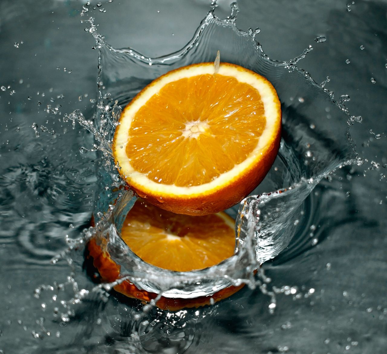 High-speed capture of an orange slice splashing into clear water.
